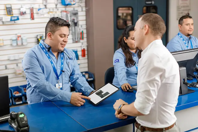 Dos personas hablando en mostrador de tienda Vendedor de sucursal mostrando catálogo de productos a cliente