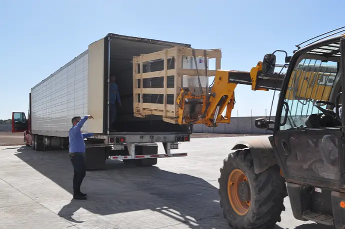 Persona colocando caja de productos dentro de un camión de entrega Un hombre está colocando una caja de productos en un camión, listo para iniciar la entrega.
