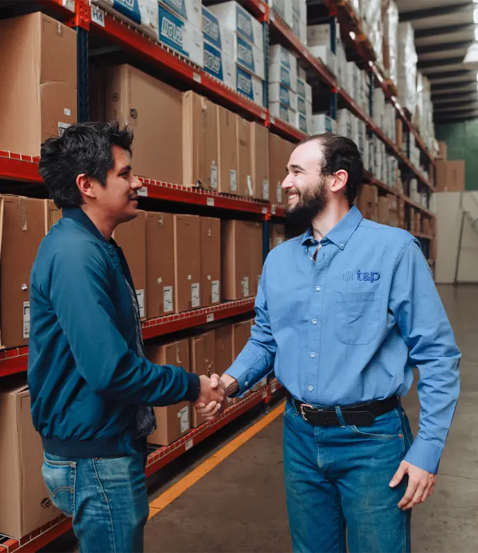 Personas estrechándose la mano Dos hombres se dan la mano en un almacén, representando un momento de negociación